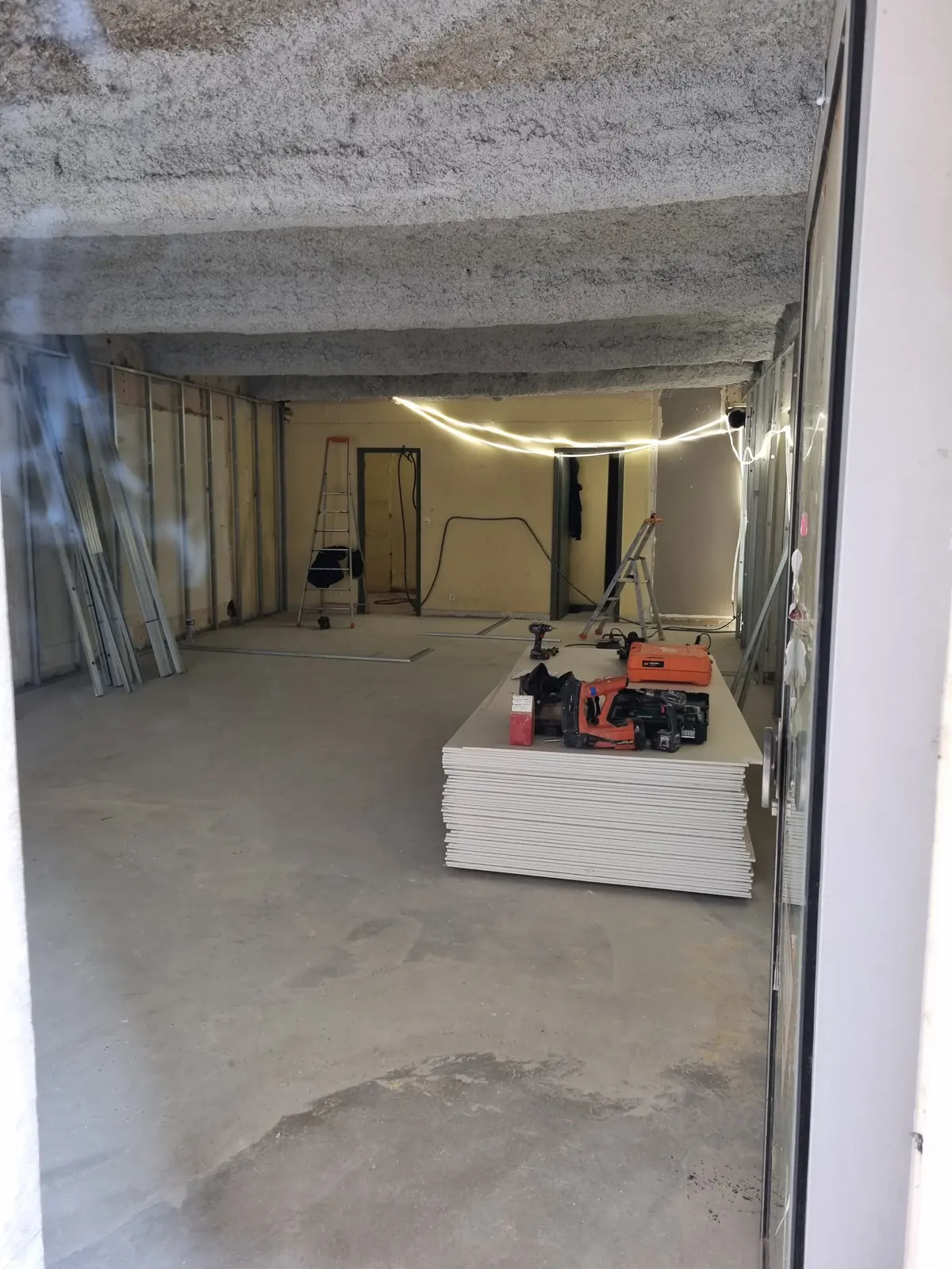 Local commercial livré brut : dalle béton, plafond brut, plaques de plâtre en attente au sol