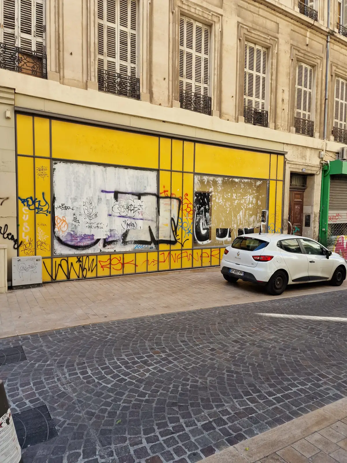 Ancienne devanture de commerce en centre-ville, façade jaune couverte de tags avant travaux