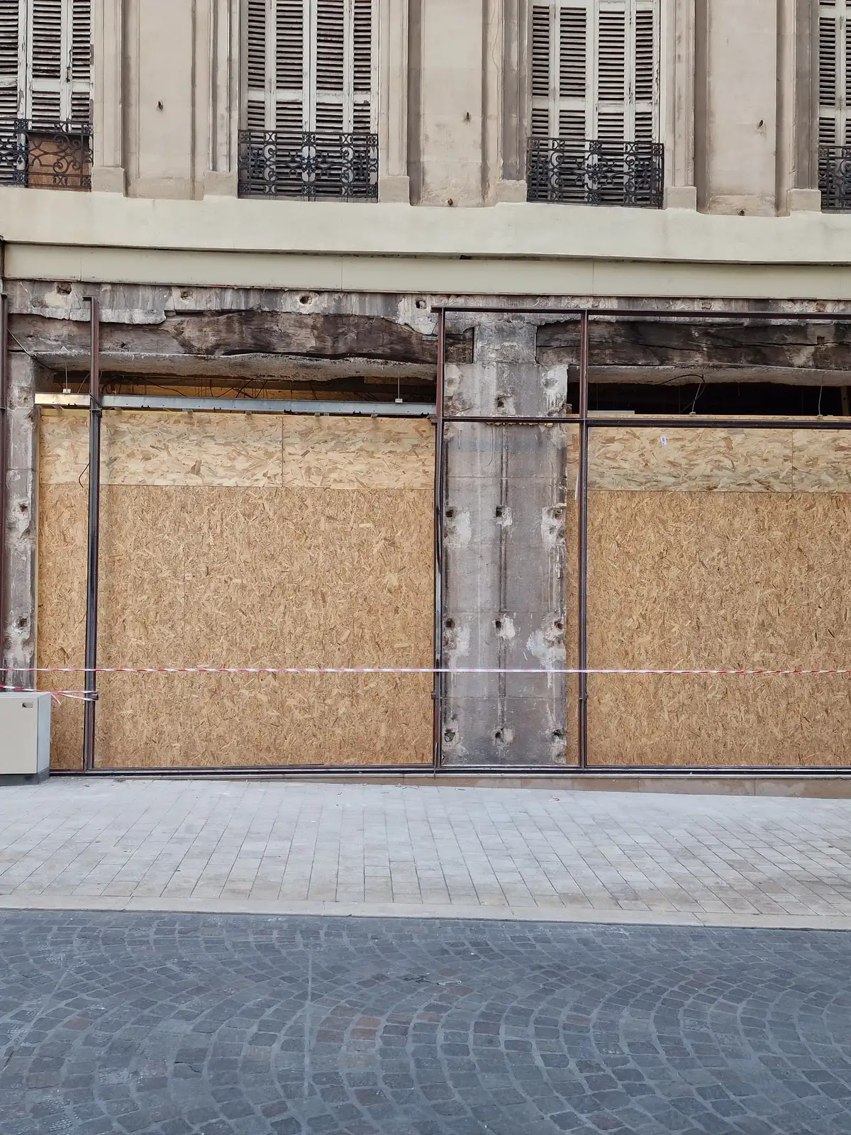 La même façade une fois la vitrine déposée, refermée par des panneaux bois ajustés à chaque travée